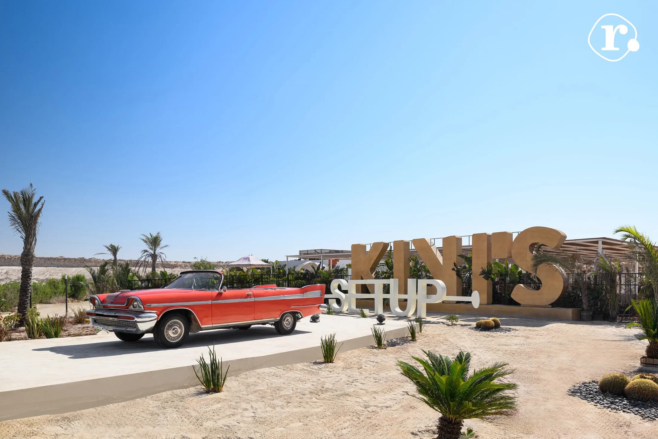 Kiki's arrival area with its sign, red car and landscaped path